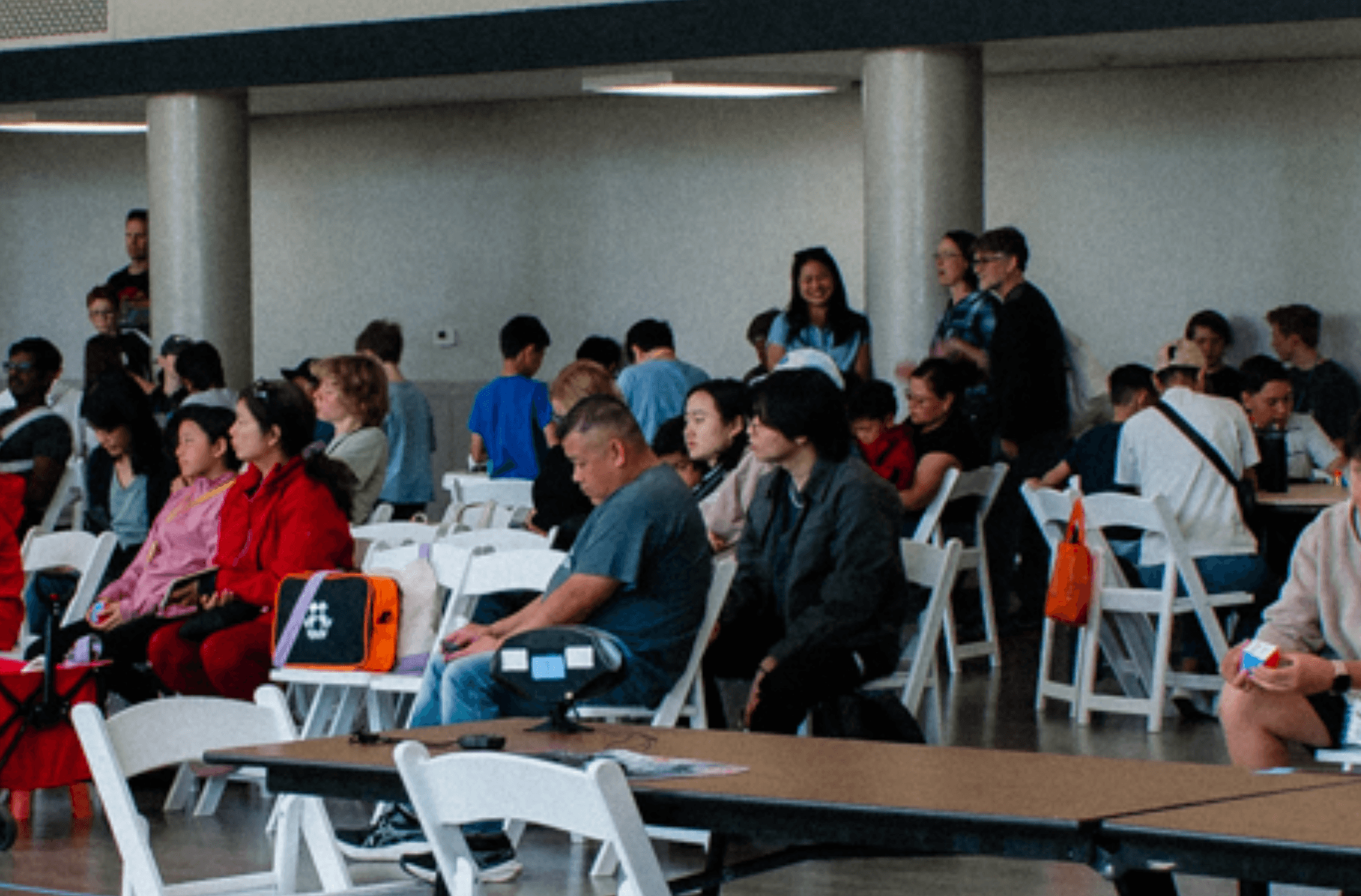 cubing competition crowd seated in white folding chairs watching solves
